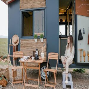 A woman enjoying her blue tiny home on wheels.