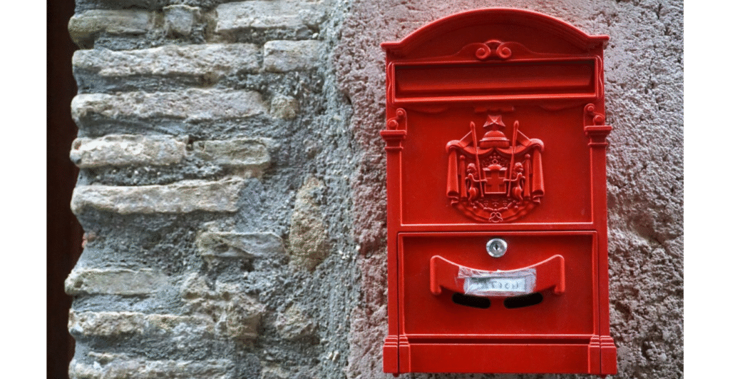 Red mailbox on a stone wall.