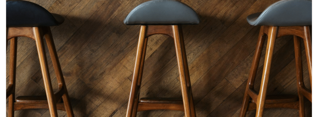 Three bar stool with blue seat and wood legs.